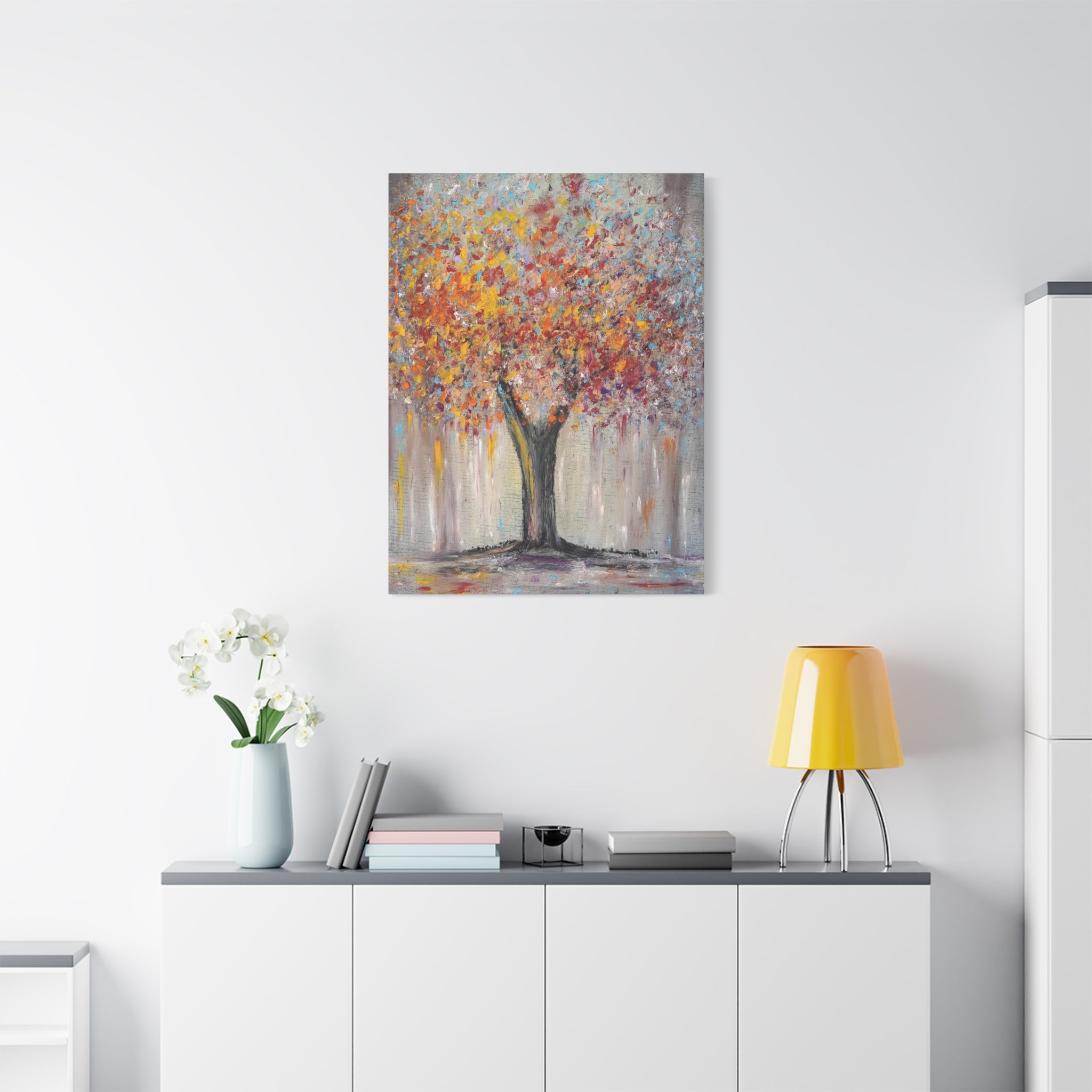 Colorful abstract tree Canvas Matte Art printed on a white wall above a white cabinet with decorative items.