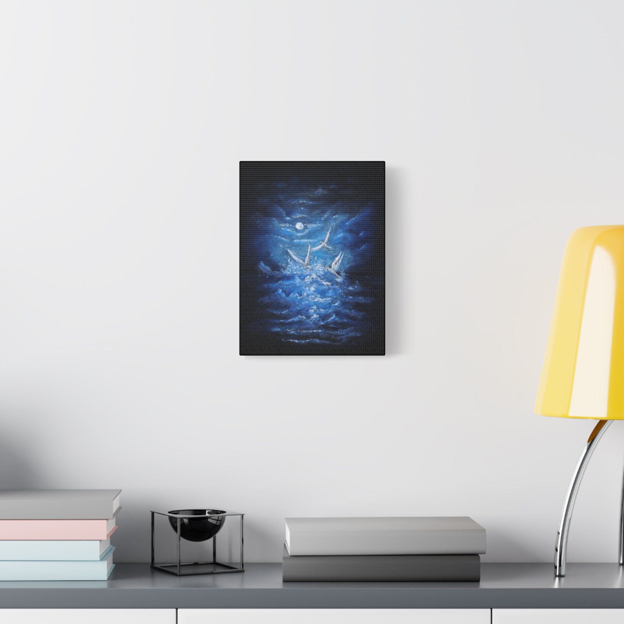 Canvas matte stretched artwork of the ocean and white birds flying above the waves with a moon on a white wall above a desk.
