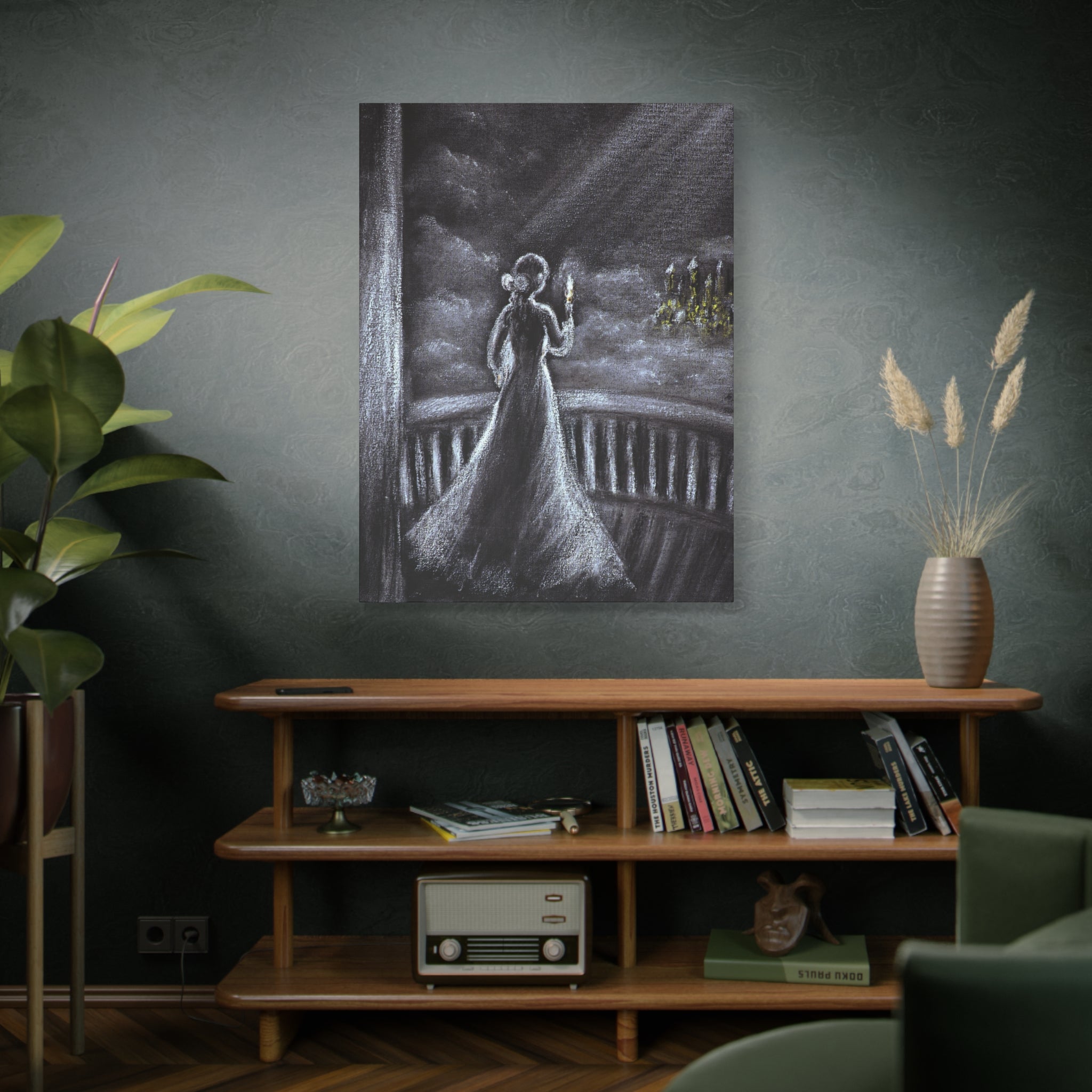 Canvas printed artwork of a woman in a long white dress and a candle in a mystery night ambient on a wall above a wooden shelf with books and decor.