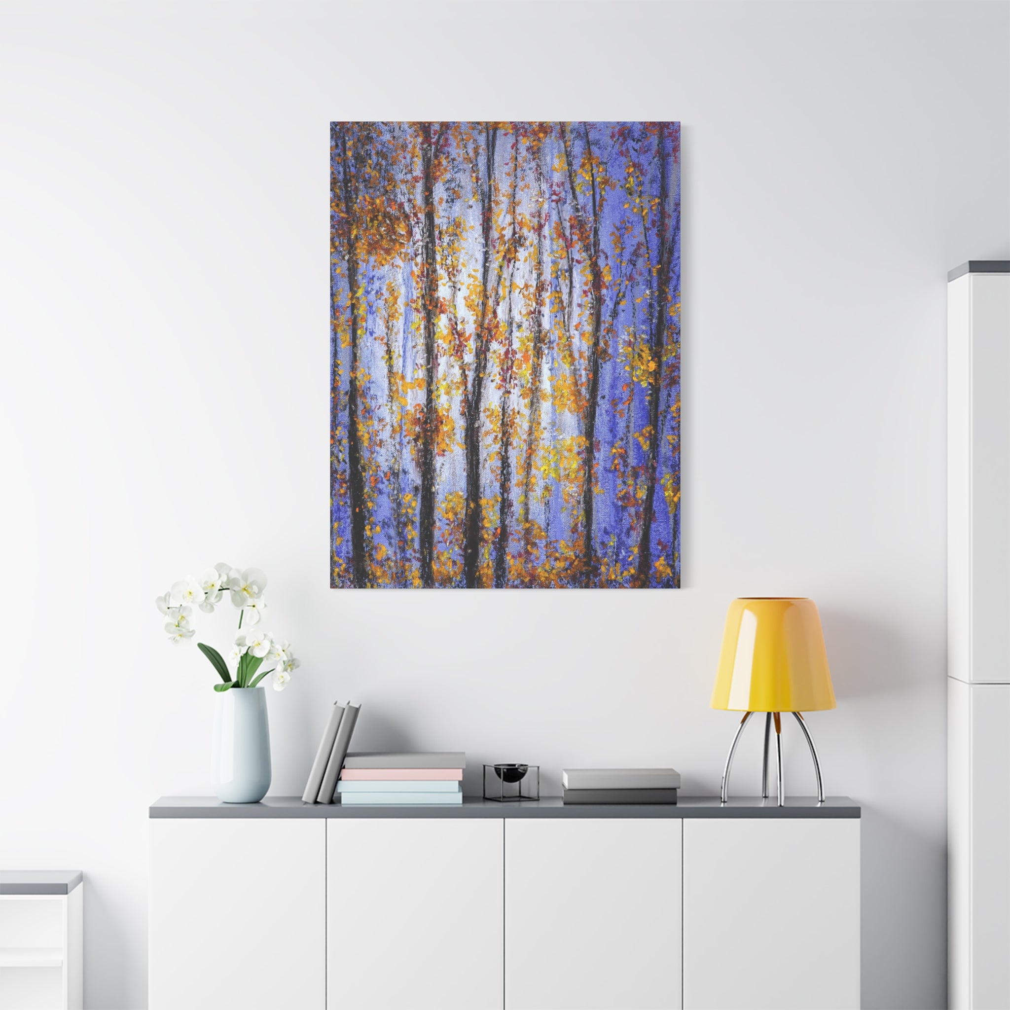 Autumn Aspens Matte Stretched Canvas print of a forest scene with blue sky and yellow trees hanging on a white wall above a white cabinet.
