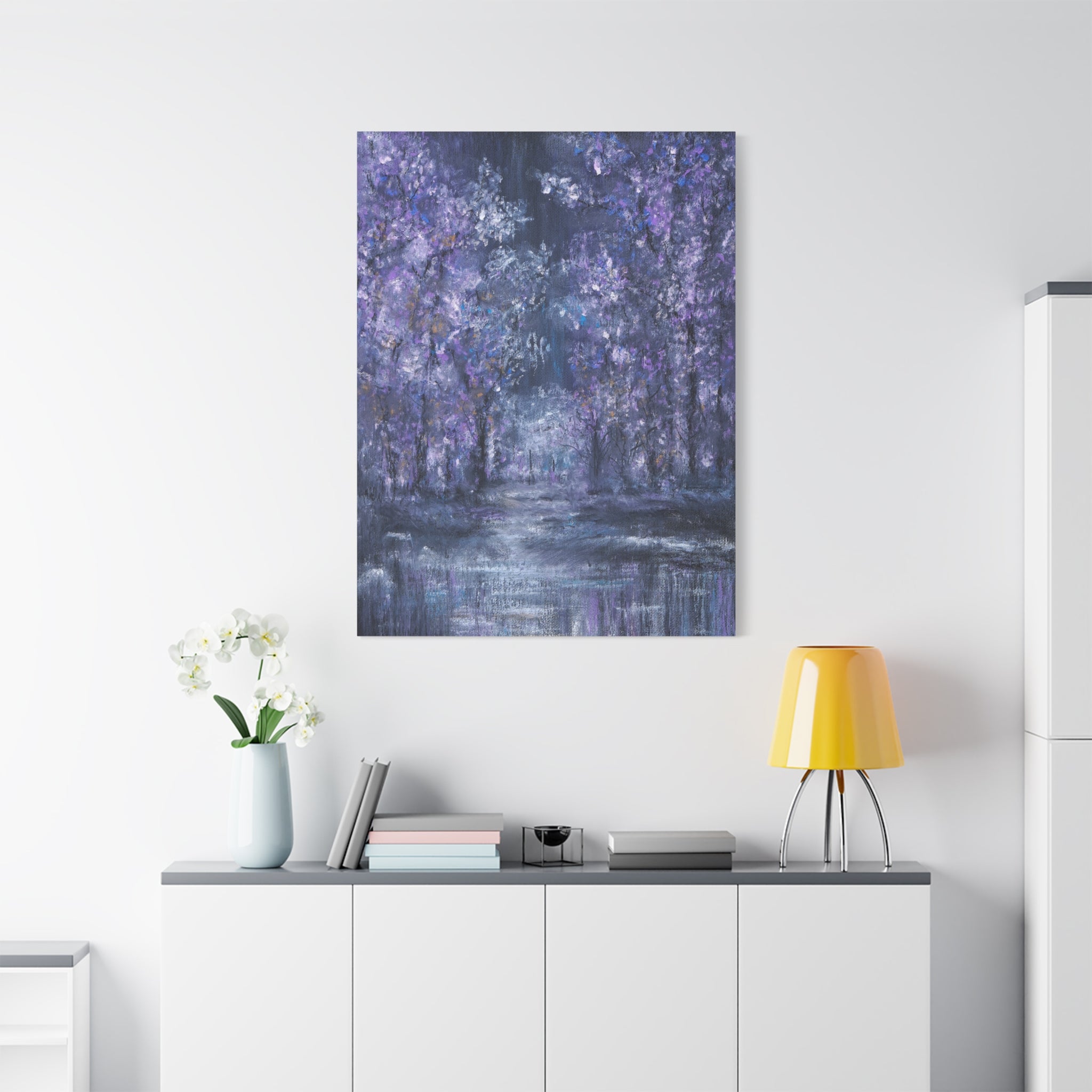 Abstract Canvas Art printed of a forest scene in white, purple and blue tones on a white wall above a white cabinet with decorative items.