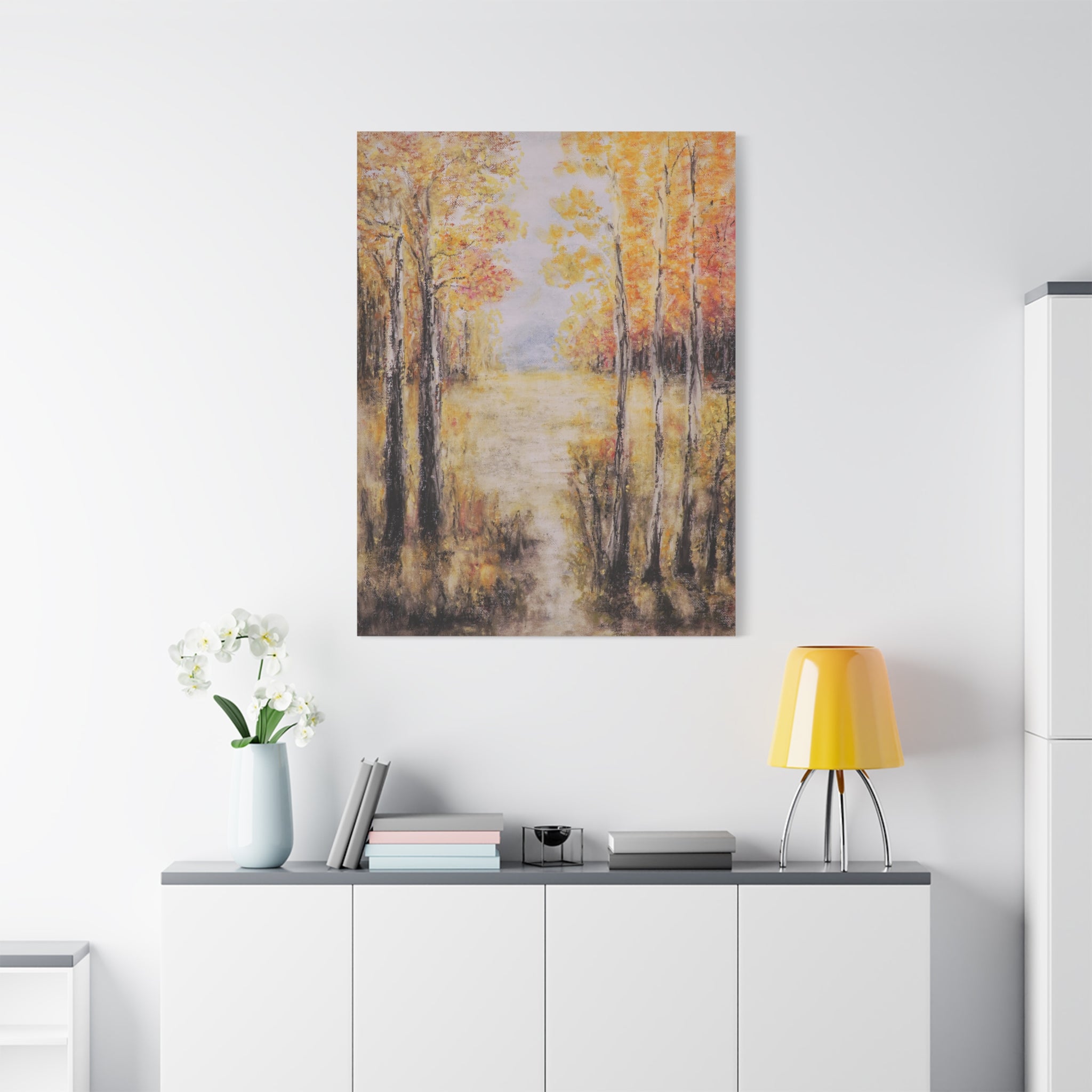 Canvas matte stretched print of autumn trees in orange and yellow tones on a wall above a white cabinet with decorative items.